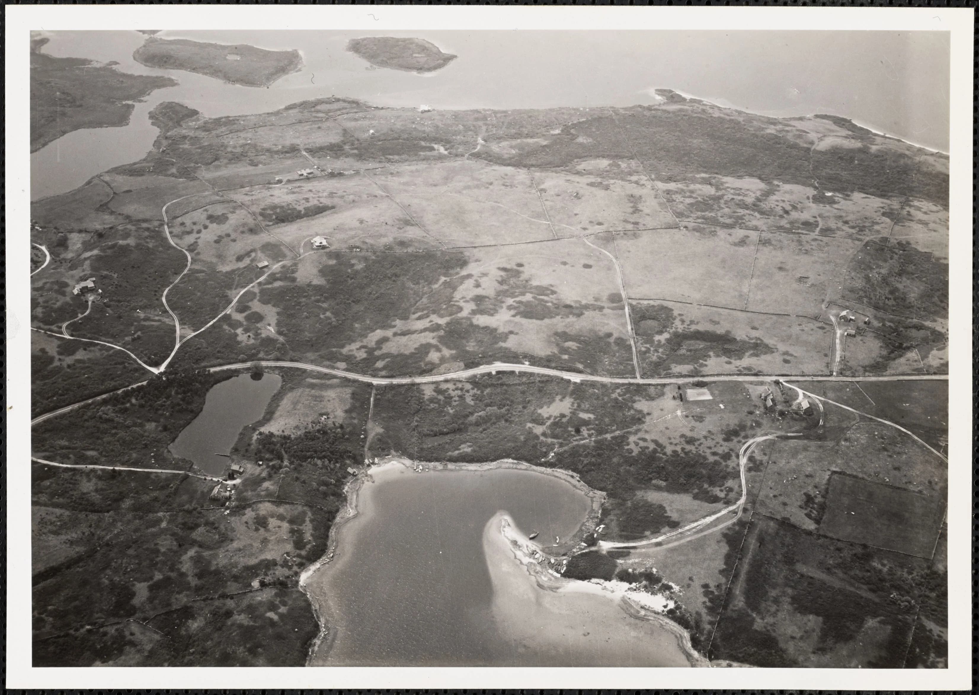 Historic black-and-white aerial view of Squibnocket Pond, roads, fields, and coastline.